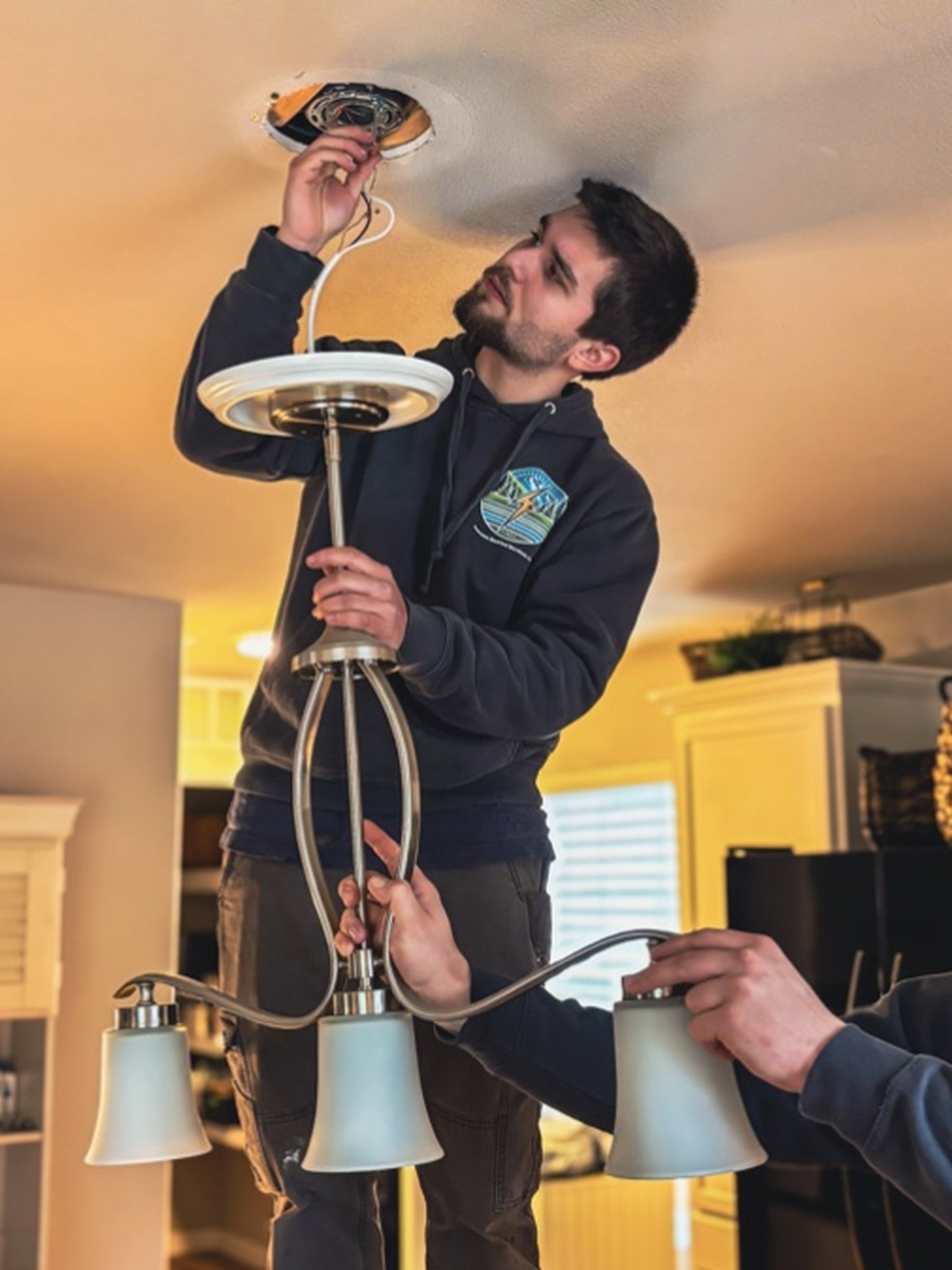 johnson-electric-services-electrician-concrete-wa Johnson Electric Services electrician installing a ceiling light fixture in a home in Concrete, WA.